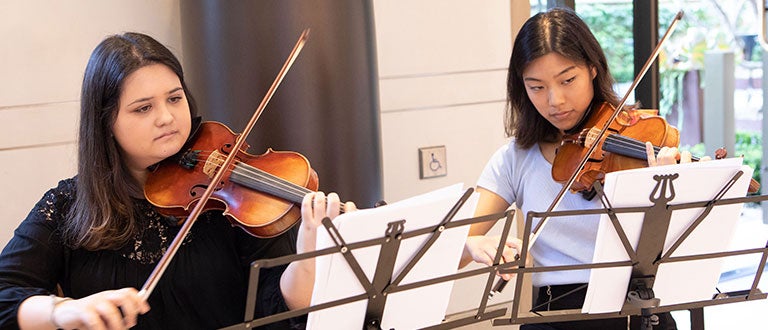 Two students expressively perform their violins